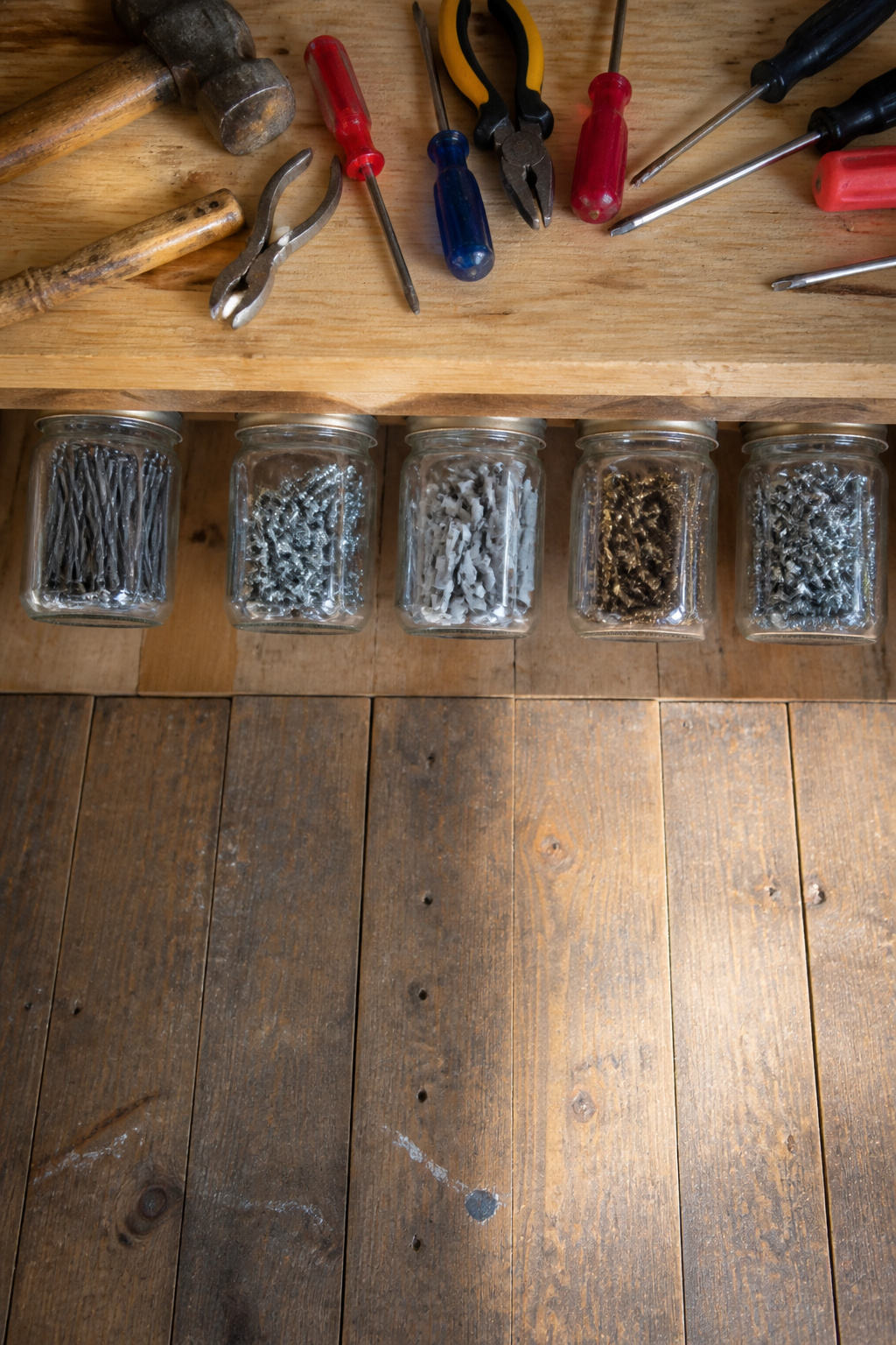 Clear jars attached under a shelf, holding various small parts and fasteners.