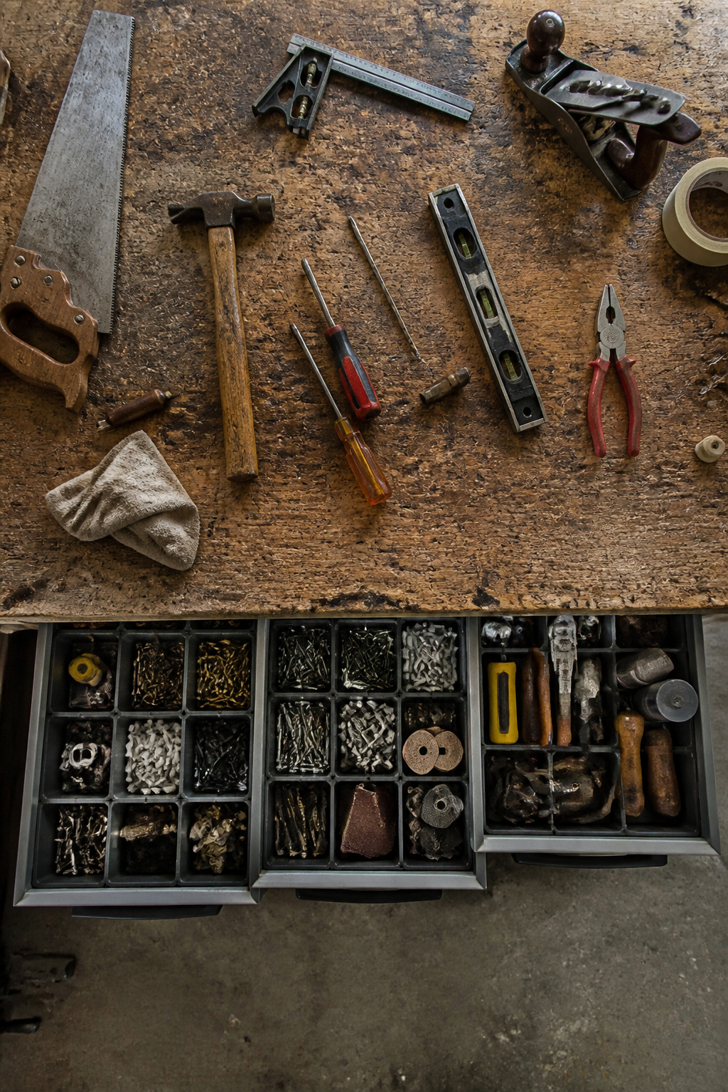 Drawer organizers filled with socket sets and small tools under a workbench.