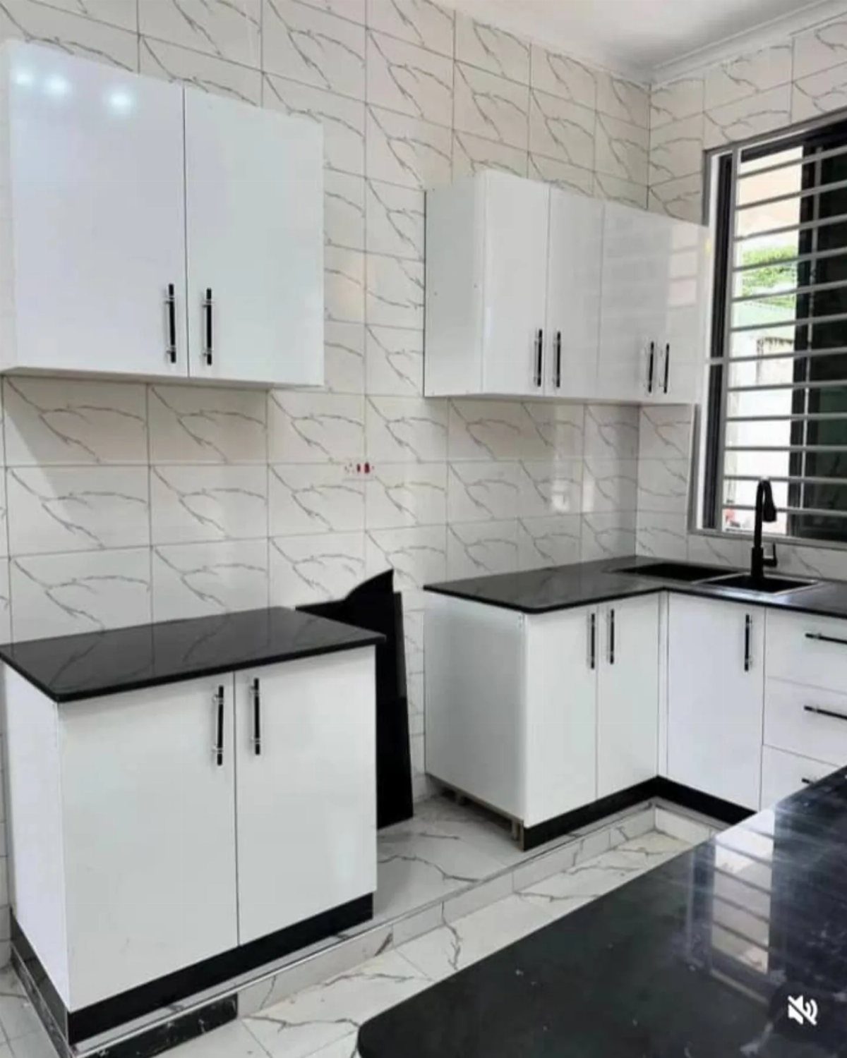 Nigerian Kitchen Design: 25 Ideas for Modern Functional Spaces 5 White flat-panel kitchen cabinets with black countertops and marble-patterned wall tiles.