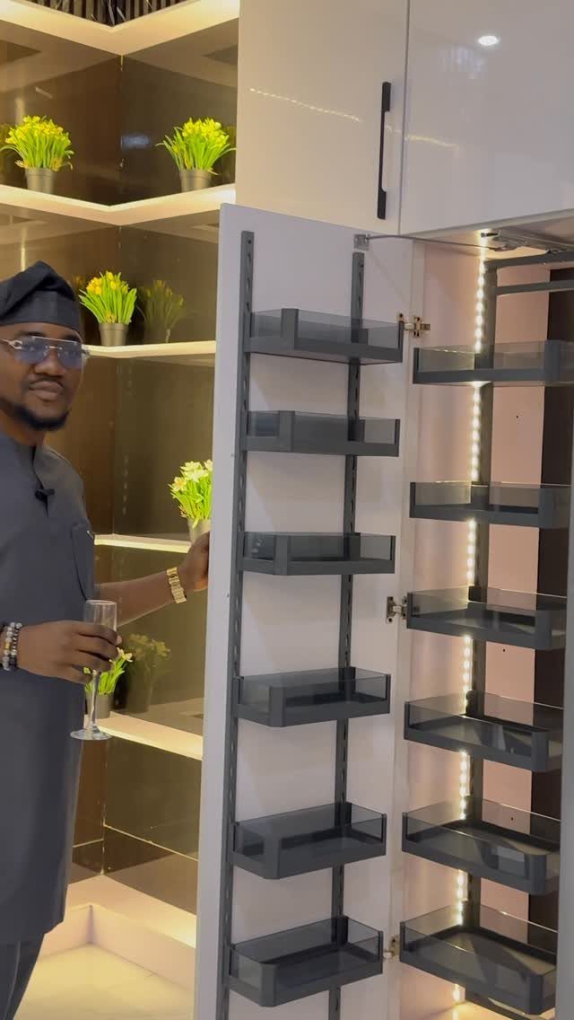 Nigerian Kitchen Design: 25 Ideas for Modern Functional Spaces 18 Man standing by a modern white kitchen cabinet with a pull-out spice rack.