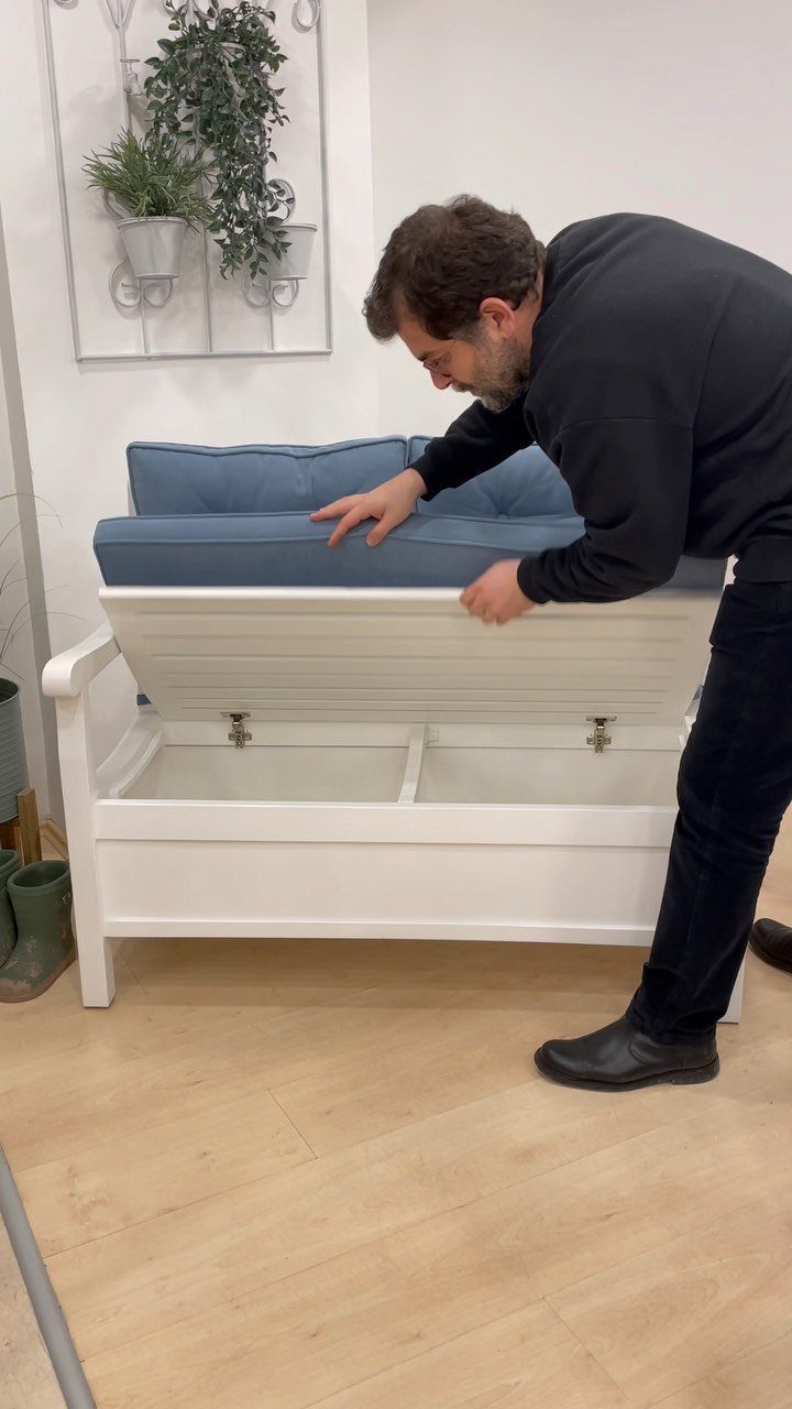 Living Room Storage Cabinet Ideas: 14 Styles That Fit Any Space 14 White wooden storage bench with blue cushions being opened by a man.