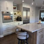 White kitchen island with marble countertop and grey base in a modern kitchen.