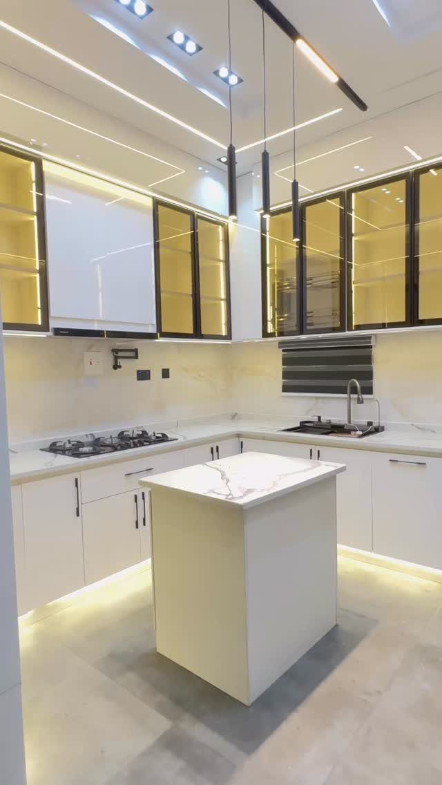 Modern white glossy kitchen cabinets with yellow glass upper cabinets and marble island.