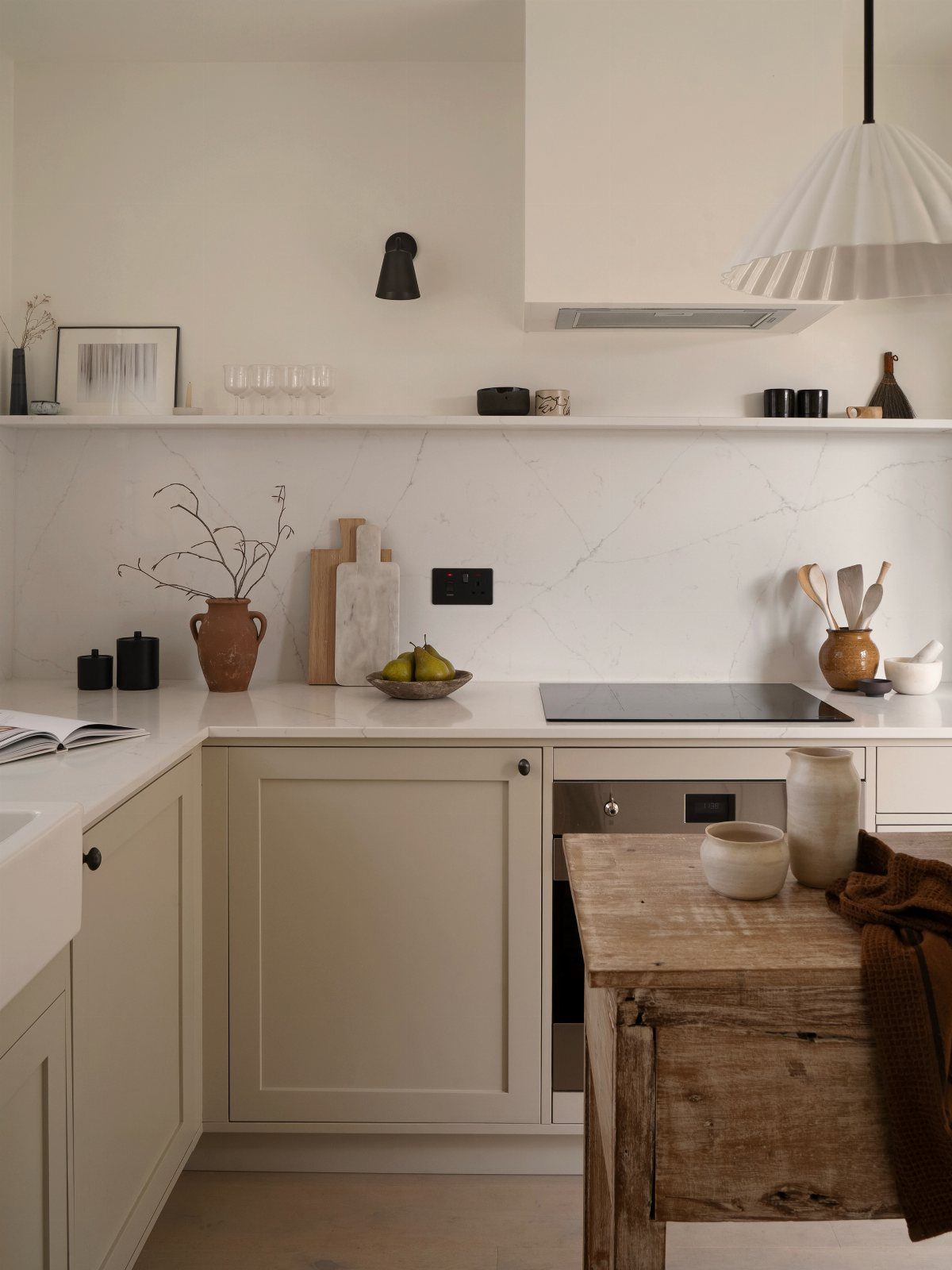 White marble kitchen counter with beige cabinets and a small wall-mounted storage shelf.
