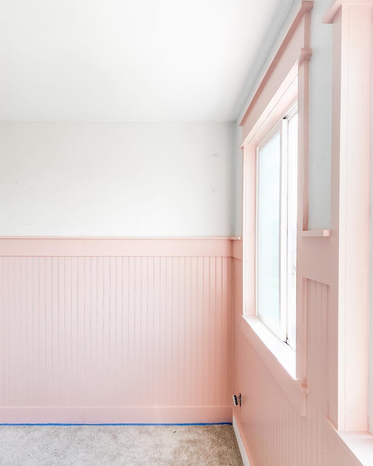 Pink painted beadboard half wall with white upper wall and matching pink window trim.