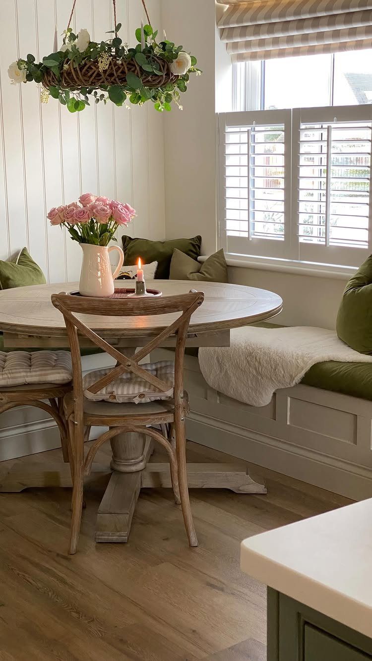 Round wooden dining table with a built-in corner bench seat and green cushions.