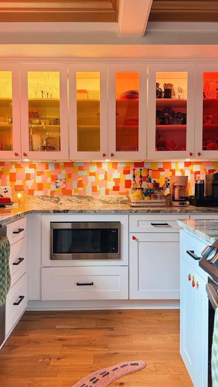 White kitchen cabinets with a colorful mosaic tile backsplash and built-in microwave.