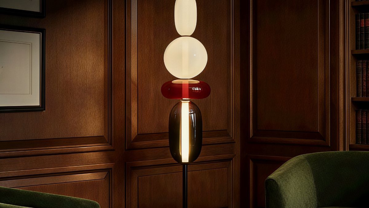 Modern floor lamp with stacked colorful glass spheres against dark wood paneling.