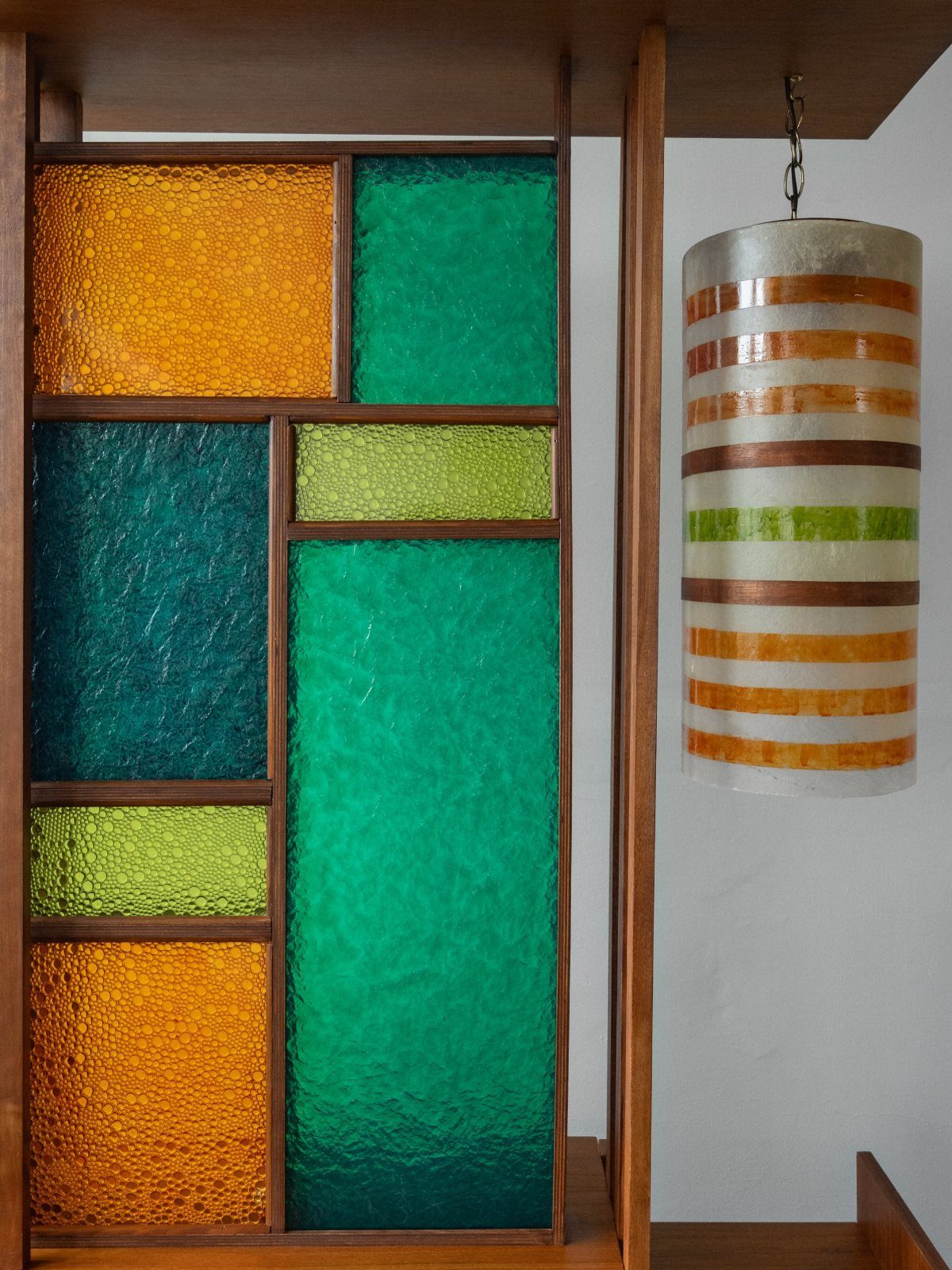 Mid-century modern lighting with colorful textured glass panels and a striped pendant lamp.