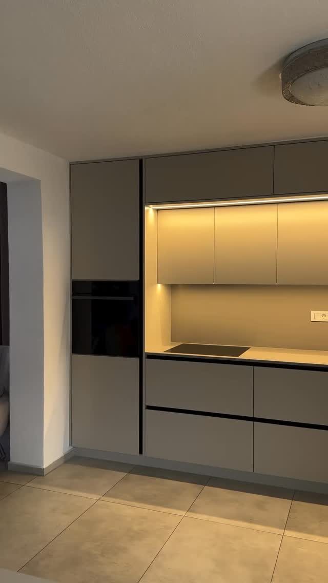 Modern small kitchen units with matte grey cabinets and integrated under-cabinet lighting.