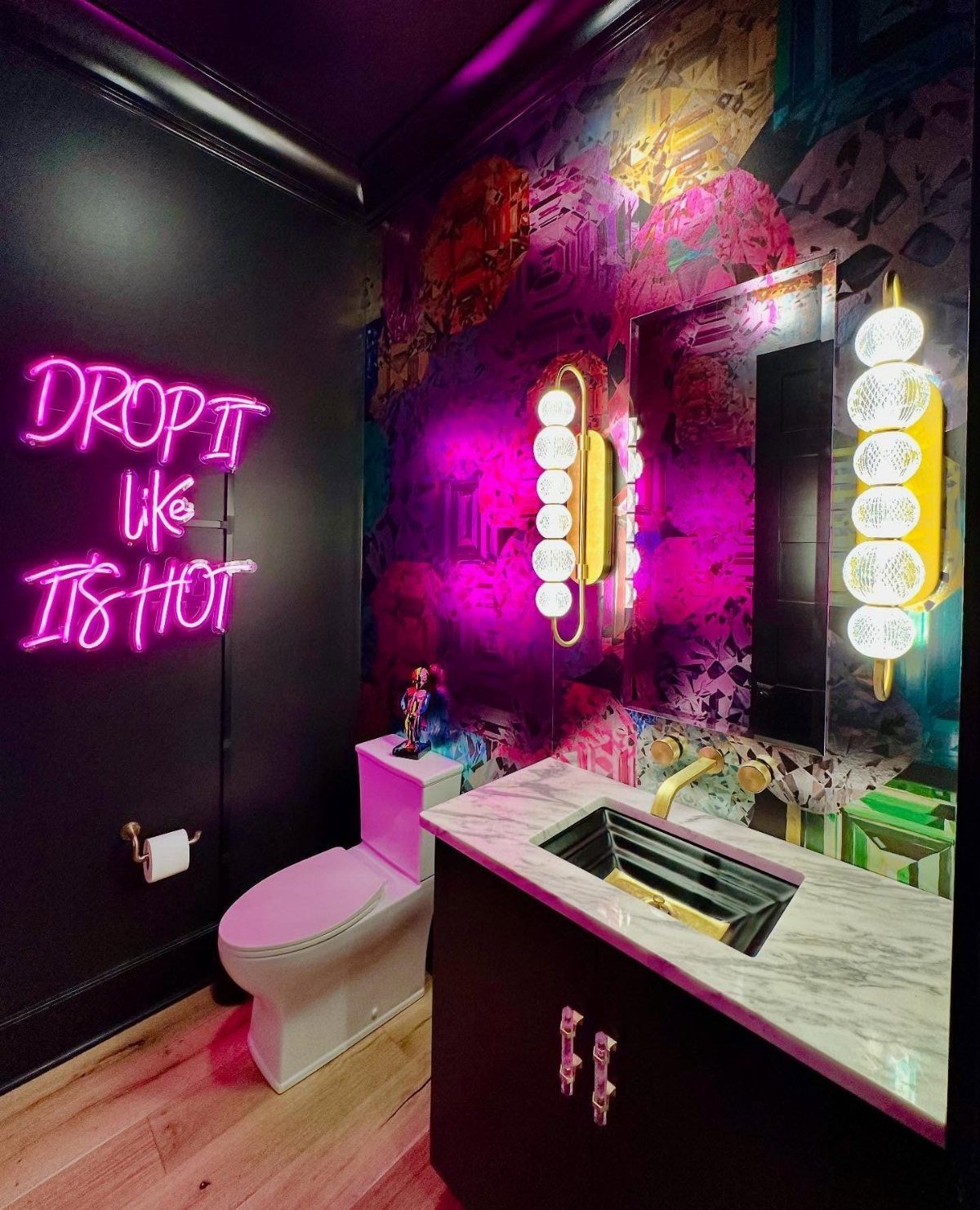 Powder room with pink neon sign, colorful mural, and marble vanity sink.