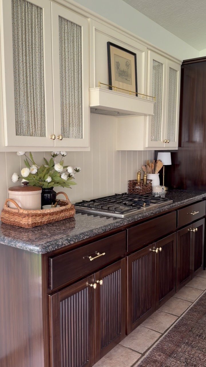 White and dark brown kitchen cabinets with gold hardware and granite countertops.