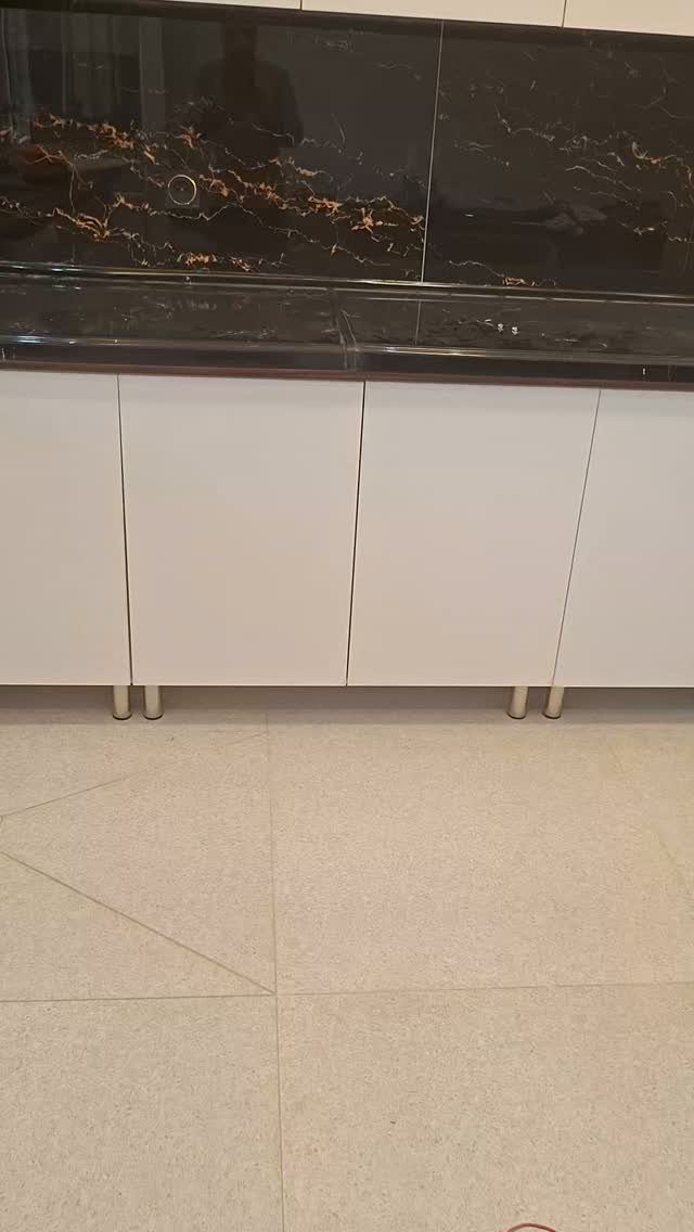 White flat-panel kitchen cabinets with a black marble countertop and backsplash.