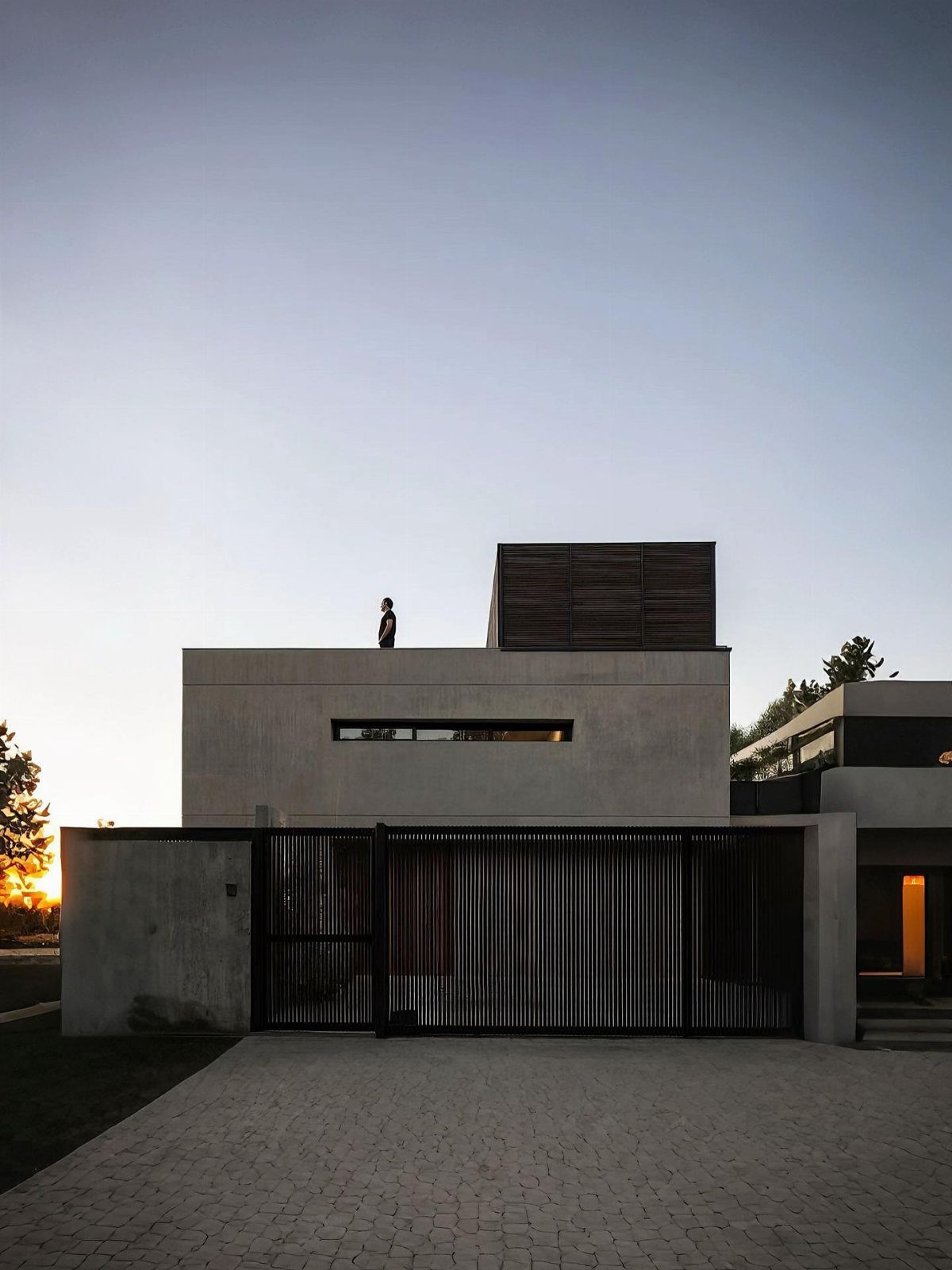 Modern concrete house with a flat roof and dark slatted wooden fence.