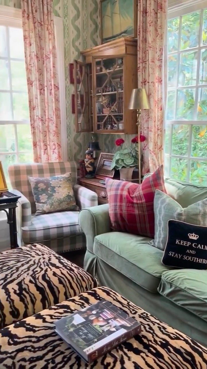 Green sofa and plaid armchair with tiger-print ottomans in a maximalist living room.