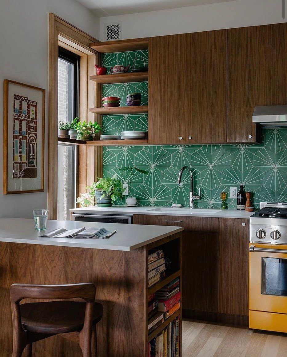 Dark wood frameless kitchen cabinets with a green geometric tile backsplash and yellow oven.