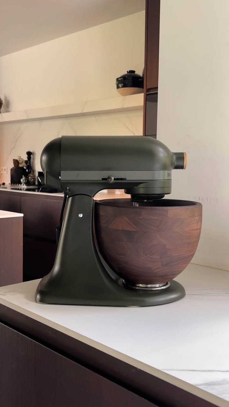 Green KitchenAid with Wood Bowl in 10 Kitchen Settings 4 Dark green KitchenAid stand mixer with a wooden bowl on a white marble counter.