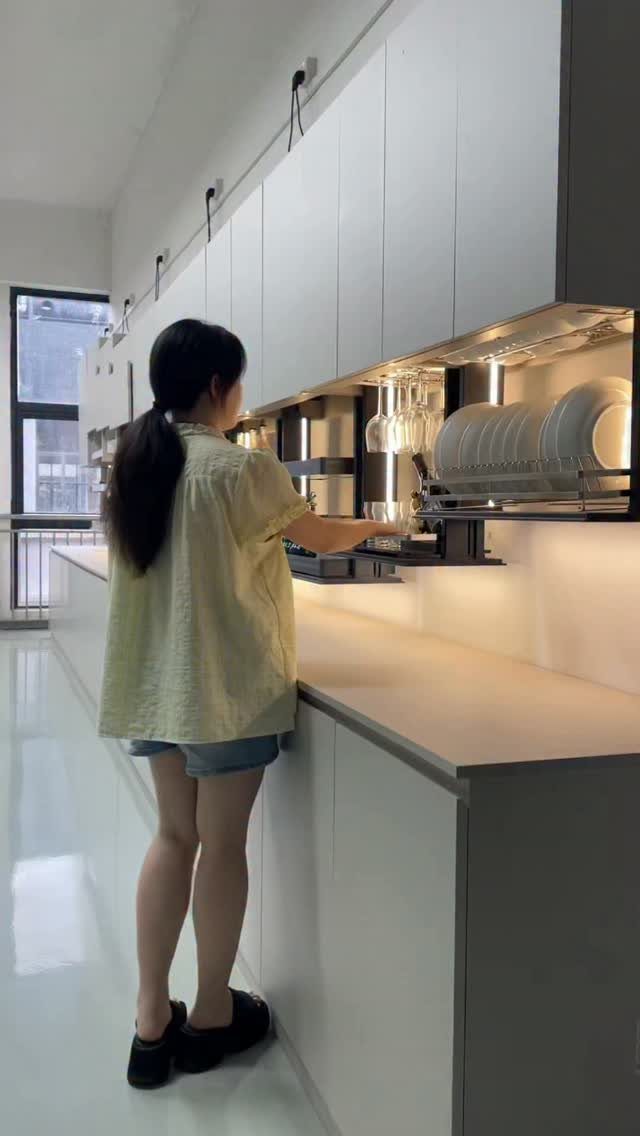 12 Kitchen Cabinet Handles Ideas to Refresh Your Space 4 Modern white kitchen cabinets with hidden hardware and a woman accessing a dish rack.