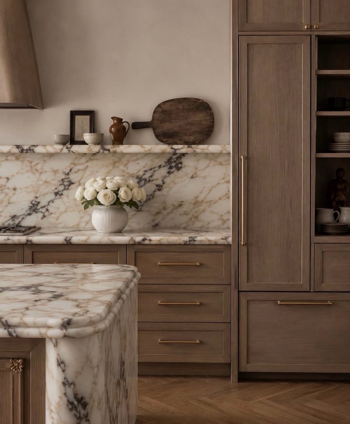 Light brown wooden kitchen cabinets with gold hardware and white marble countertops.