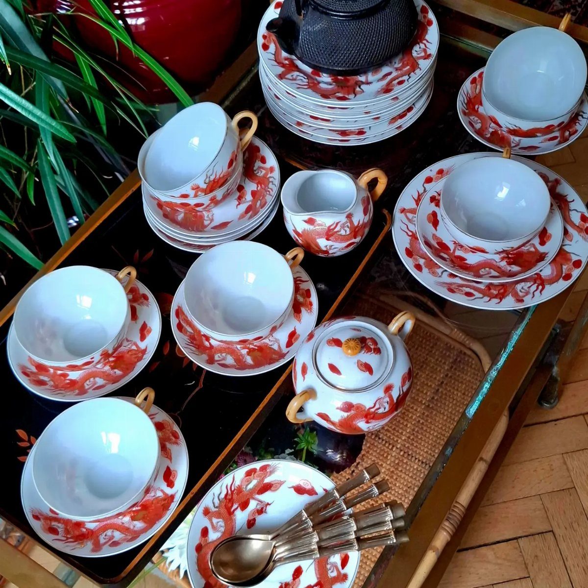 White porcelain tea set with red dragon patterns and a black cast iron teapot.