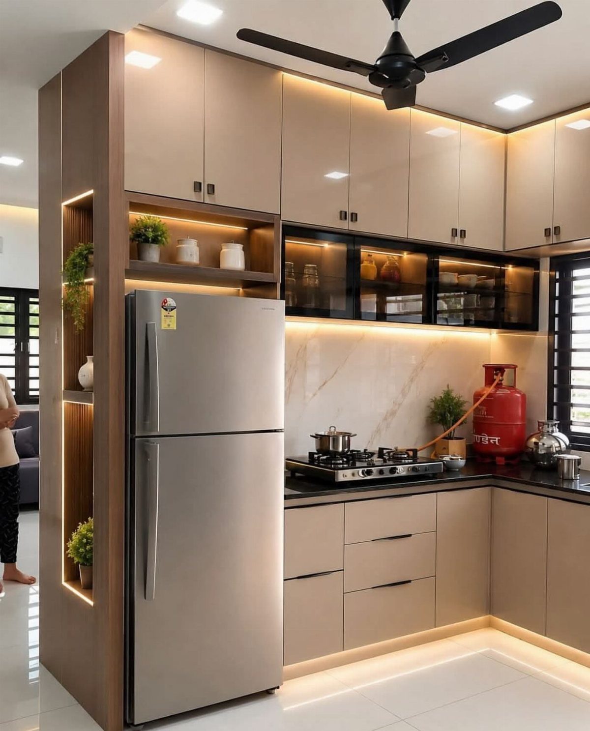 L-shaped beige kitchen cabinets with black countertops and a silver refrigerator.