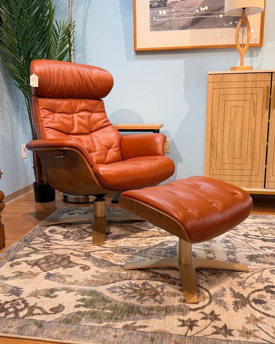 Tan leather recliner and matching ottoman on a patterned rug in a living room.