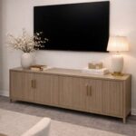 Light brown wooden media console with ribbed doors under a wall-mounted television.