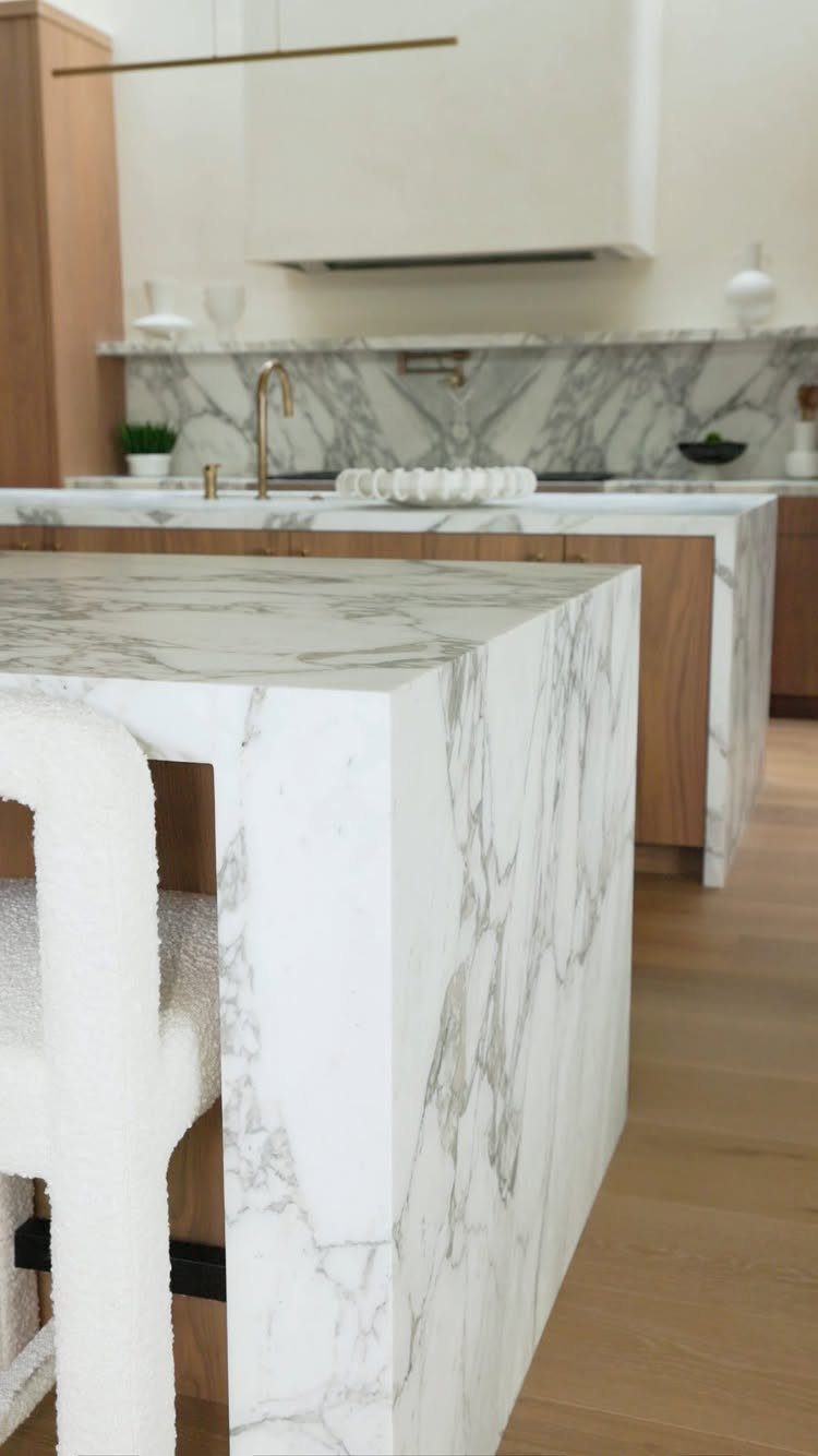 White marble kitchen island with a waterfall edge and grey veining.