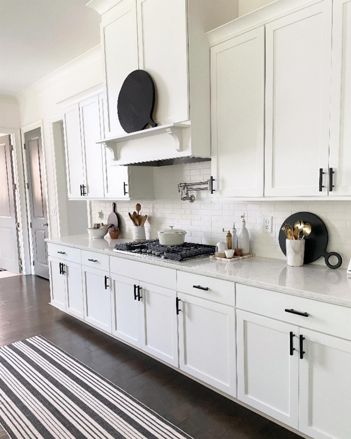12 Kitchen Cabinet Handles Ideas to Refresh Your Space 2 White kitchen cabinets featuring sleek matte black hardware and a striped floor rug.