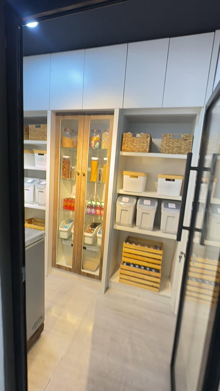 Nigerian Kitchen Design: 25 Ideas for Modern Functional Spaces 21 White kitchen pantry with wooden glass cabinets and organized storage bins and baskets.