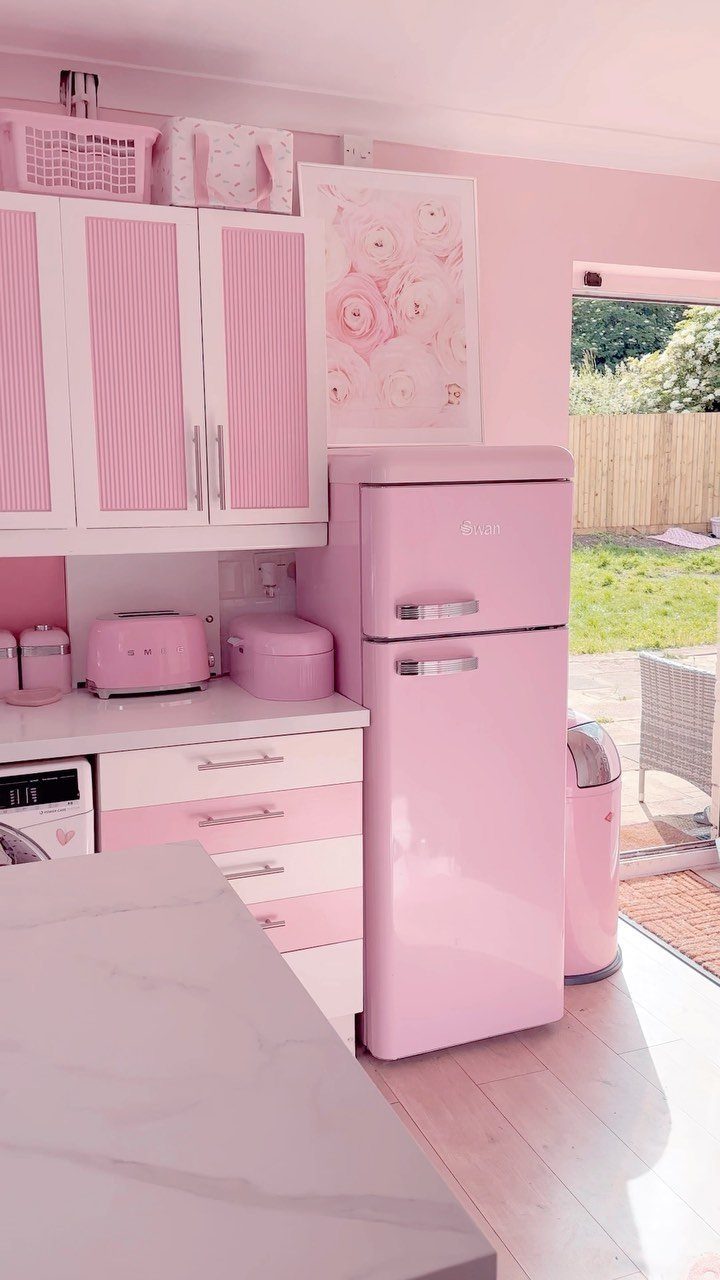 Pink retro refrigerator and toaster in a coordinated pink and white kitchen.