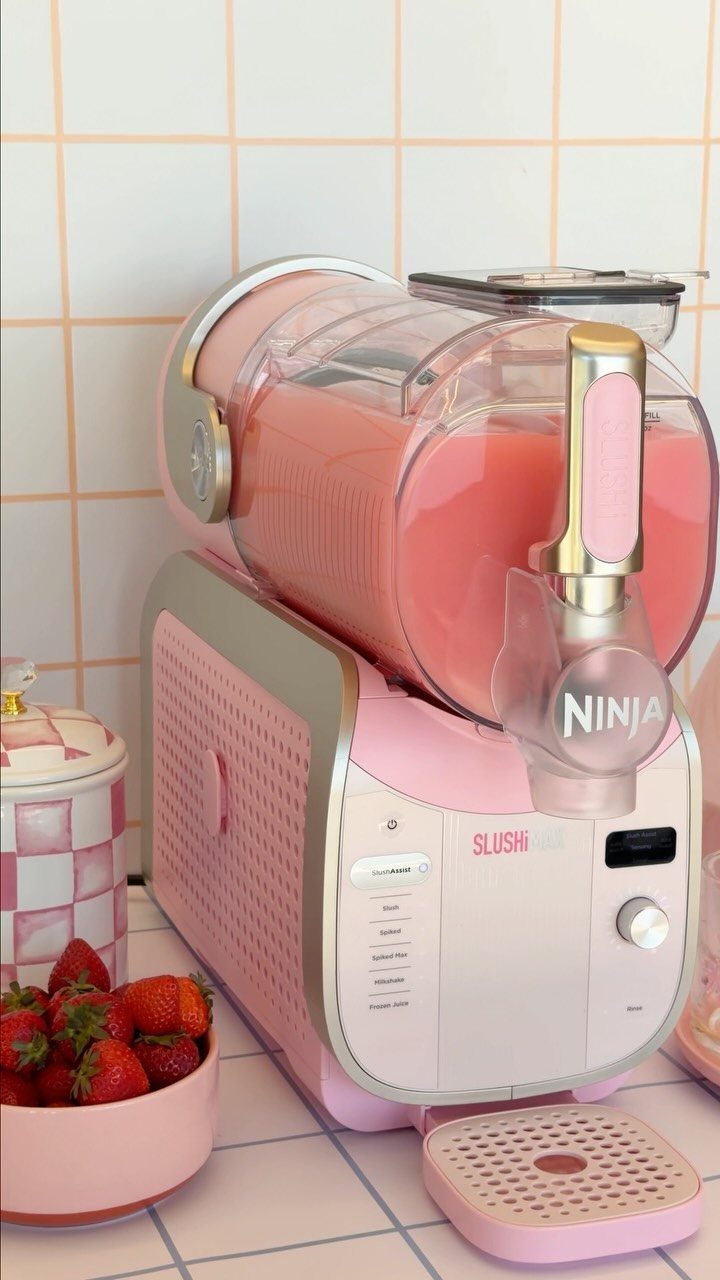 Pink Ninja Slushi machine with frozen pink drink and strawberries on tiled counter