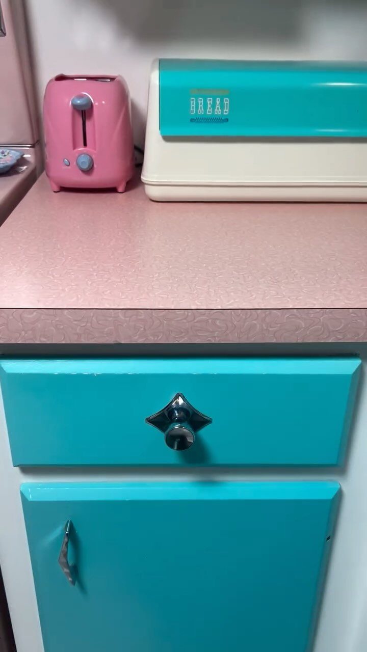 Pink retro toaster and teal bread bin on a pink kitchen countertop.