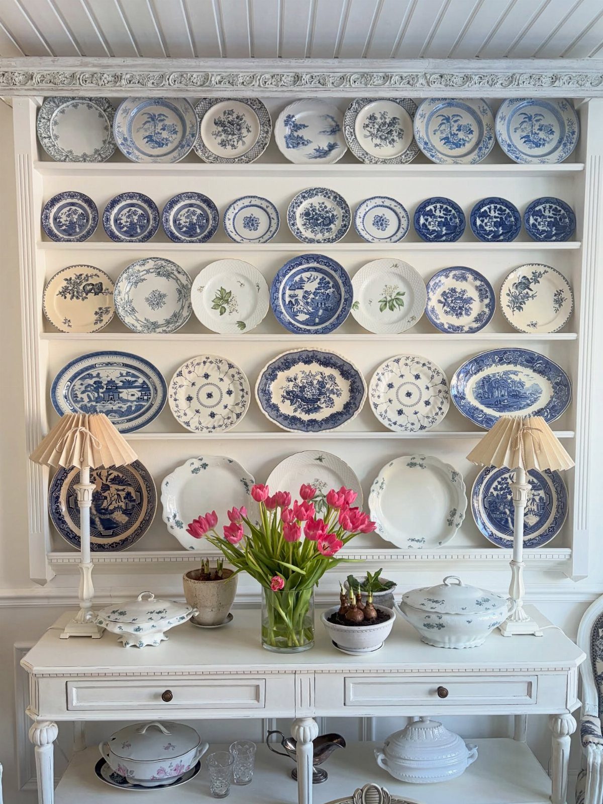 Blue and white patterned plates displayed on white built-in shelving above a console table.
