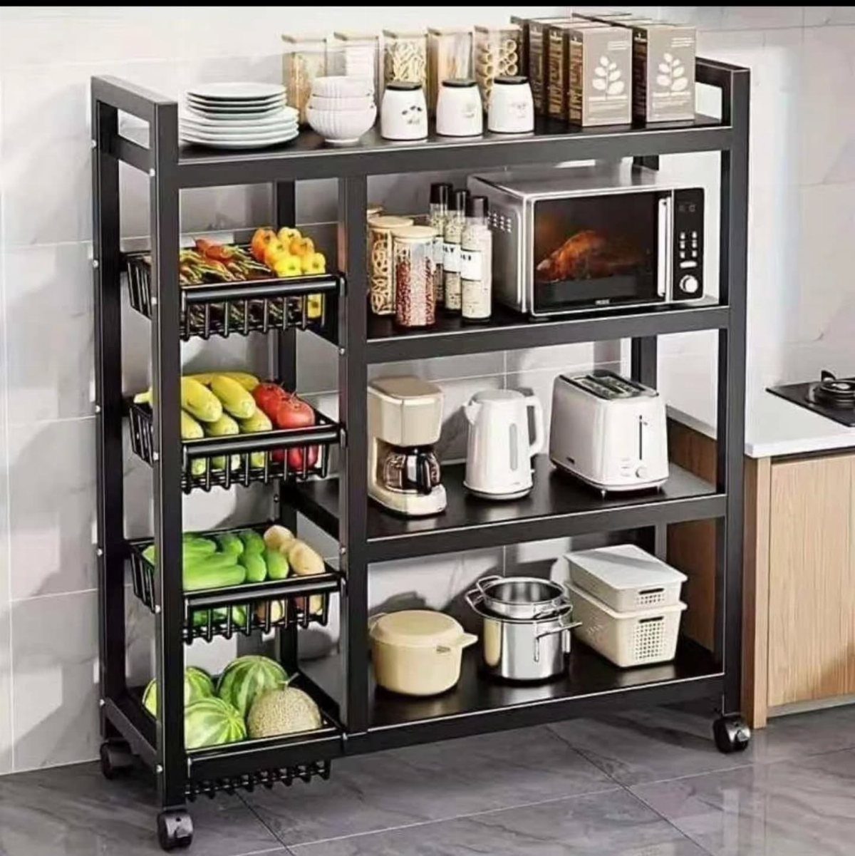 Black metal rolling kitchen cart stocked with appliances, produce, and white dishes.