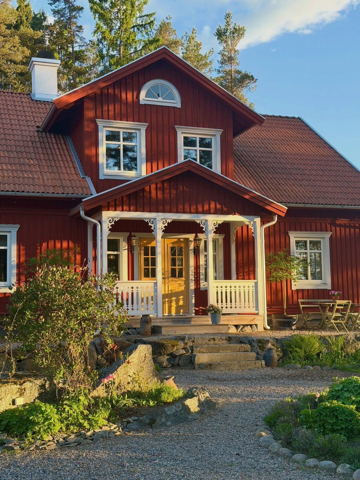 Red wooden house with white trim and gable roof in a natural setting