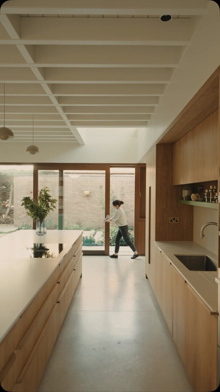 Minimalist Scandinavian kitchen with light wood cabinets, white countertops, and large glass doors.