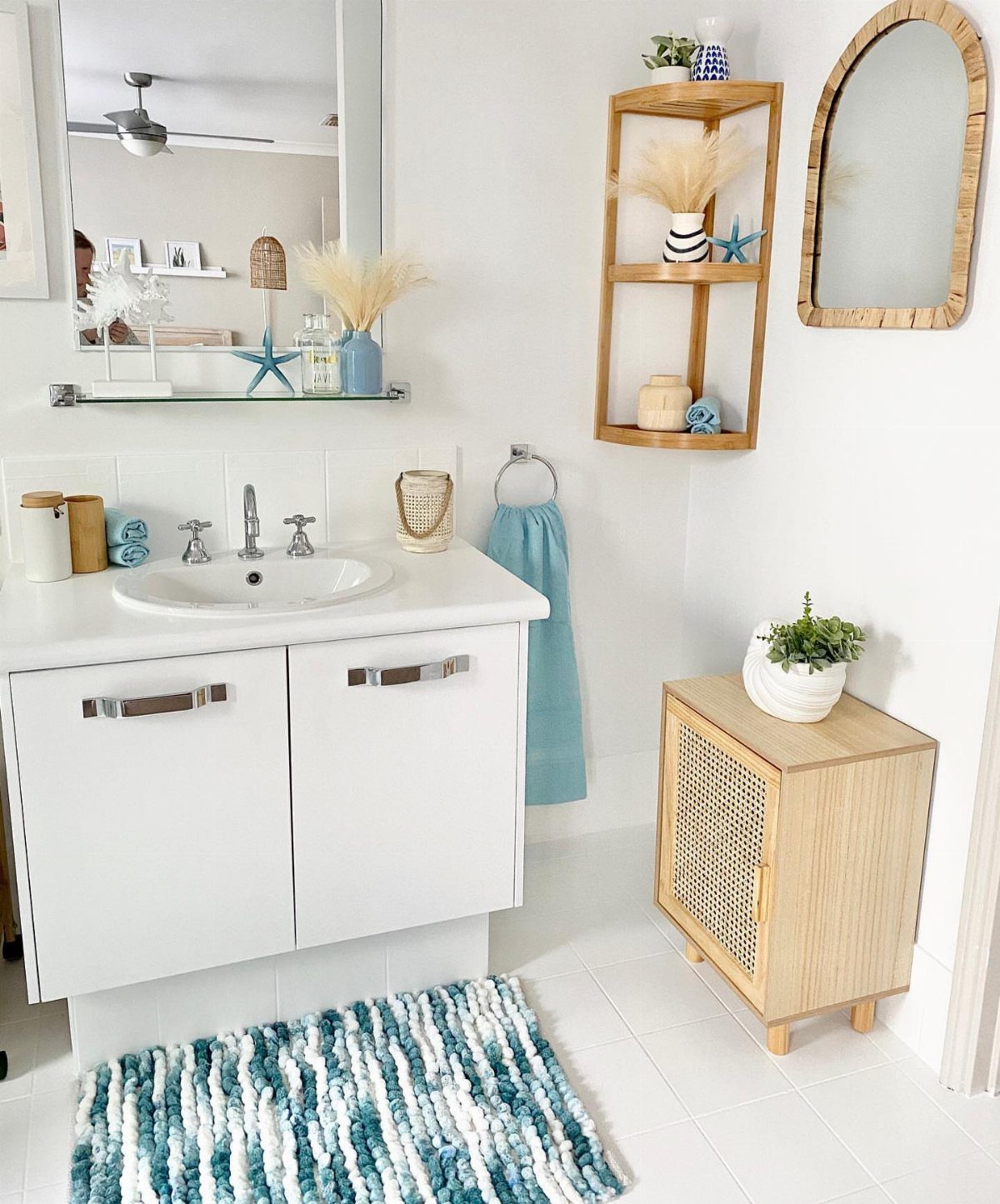 Small wooden cane cabinet used for storage next to a white bathroom vanity.