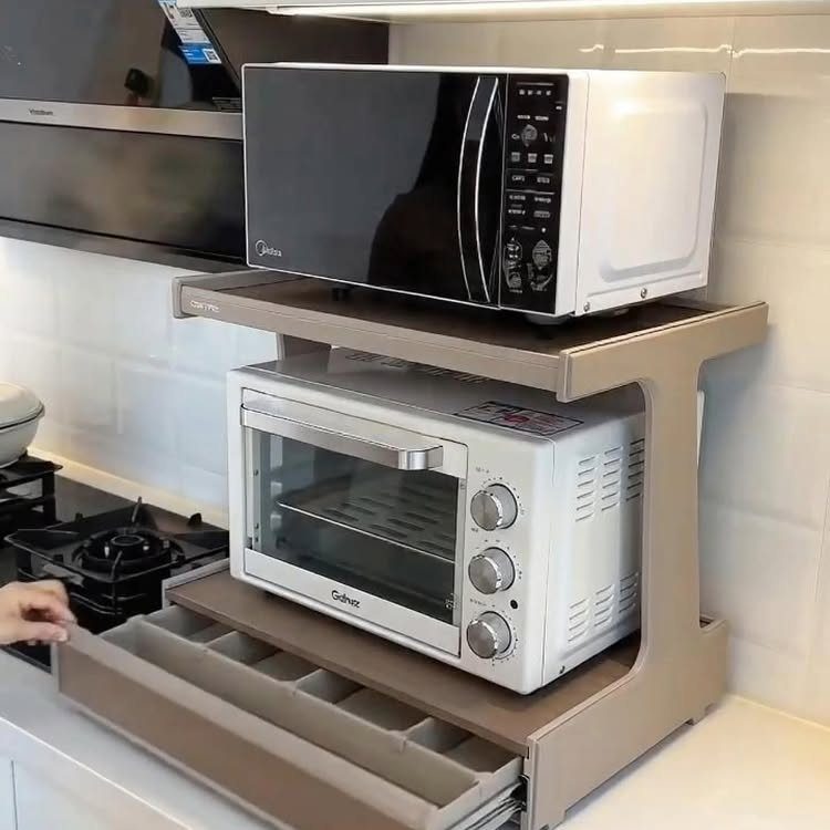 Beige metal storage rack holding a microwave and toaster oven on a kitchen counter