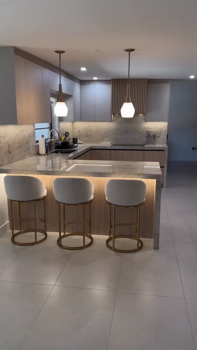 Modern small kitchen with light cabinets, grey countertops, and three white bar stools.