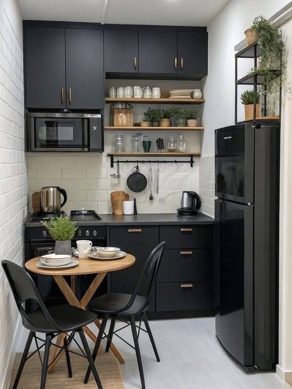 Small kitchen with matte black units, wooden shelves, and a tiny dining set.