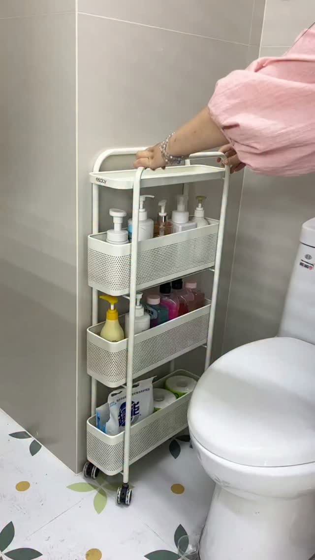 White rolling storage cart with toiletries next to a white toilet in a bathroom.