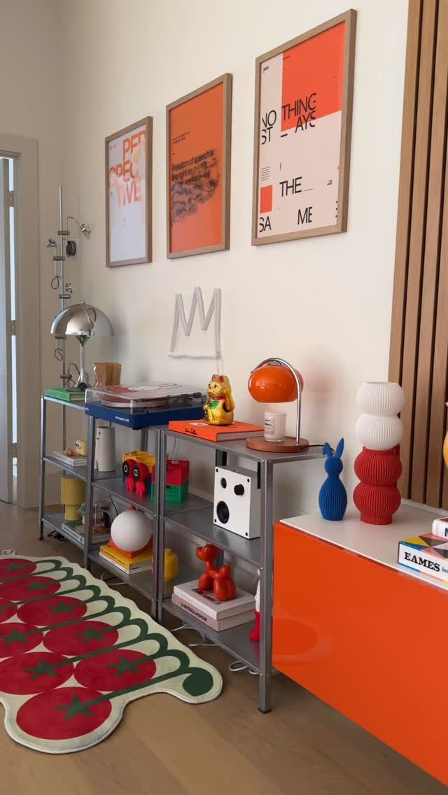 Vibrant small room with orange furniture, tomato rug, and colorful eclectic decor.