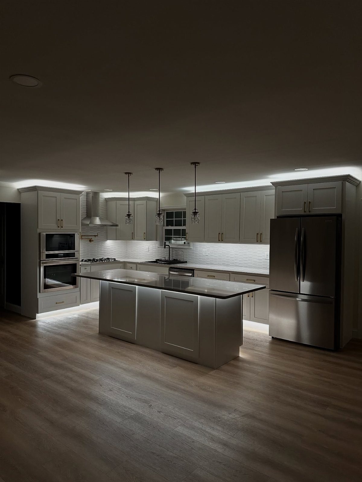 L Shaped Kitchen Cabinets: 24 Ideas for Style and Function 11 Modern kitchen with grey cabinets featuring under-cabinet task lighting and hanging pendant lamps.