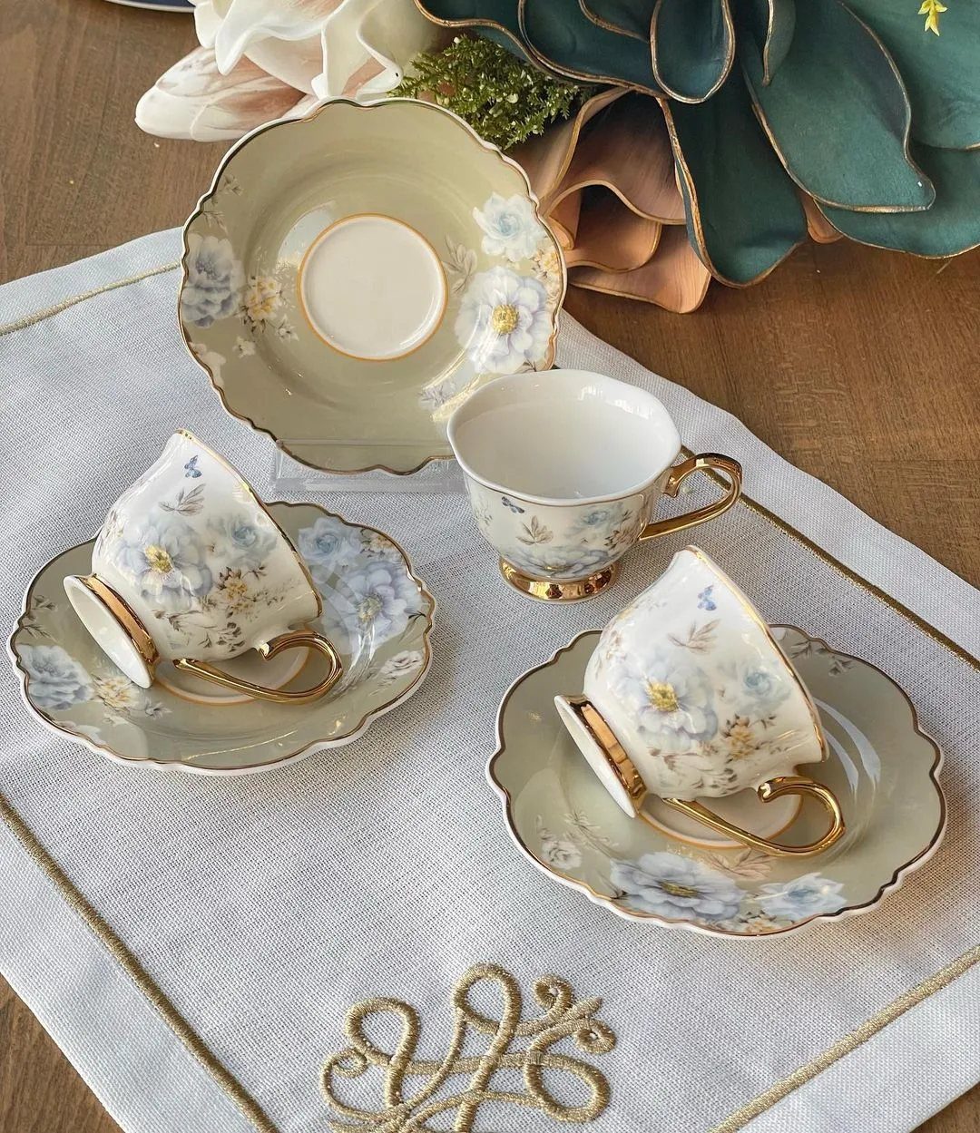Vintage porcelain tea set for two with blue floral patterns on light green china.