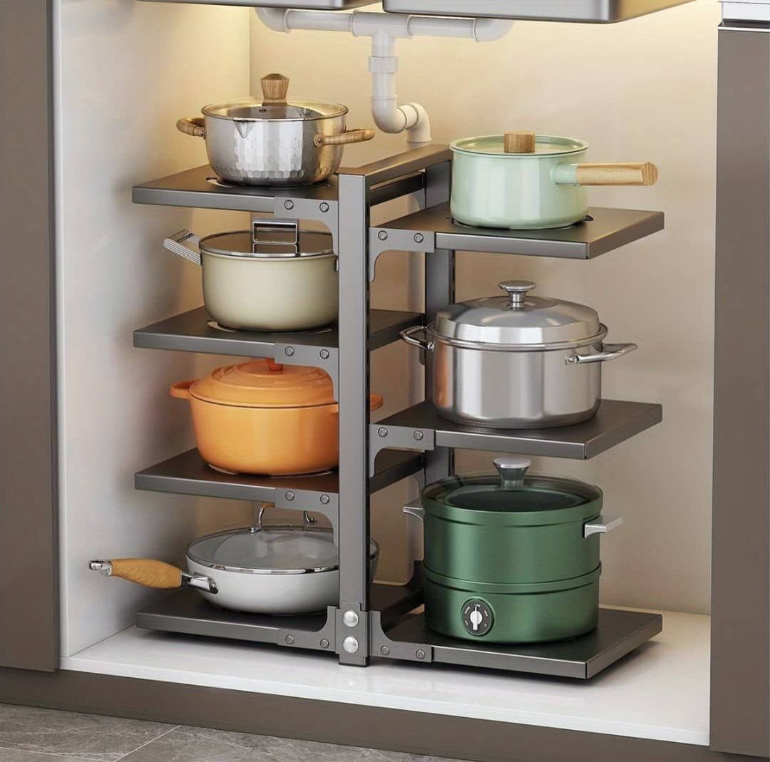 Multi-tiered grey metal shelving unit holding colorful pots and pans inside a cabinet.