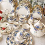 Vintage white porcelain plate set with blue floral patterns and gold gilded edges.