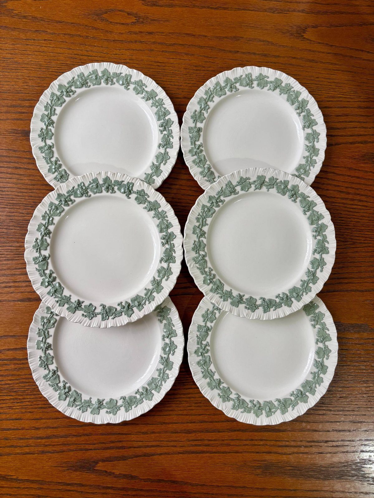 Vintage Plate Set Ideas: 12 Timeless Styles for Your Table 4 Six white ceramic plates with green strawberry vine patterns on a wooden table.