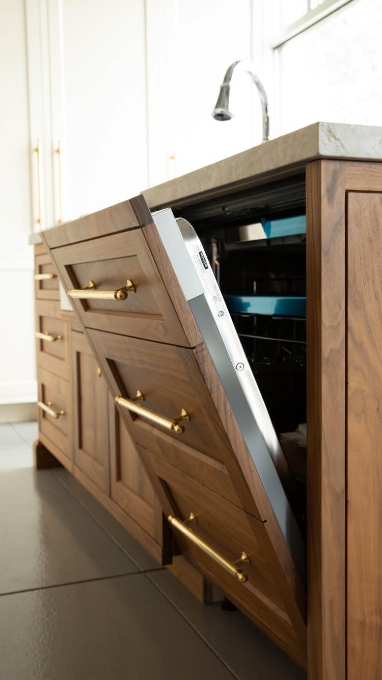 Wood-paneled dishwasher door partially open in a kitchen with matching wooden cabinetry.